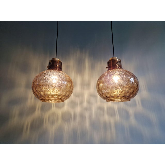 Pair of brass and smoked blown glass pendant lights, produced by the german manufacturer glashütte limburg in the 1970s....