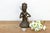 A compelling mid-scale sculptural antiquity portraying a stylized warrior holding a curved ceremonial weapon, covered in a...