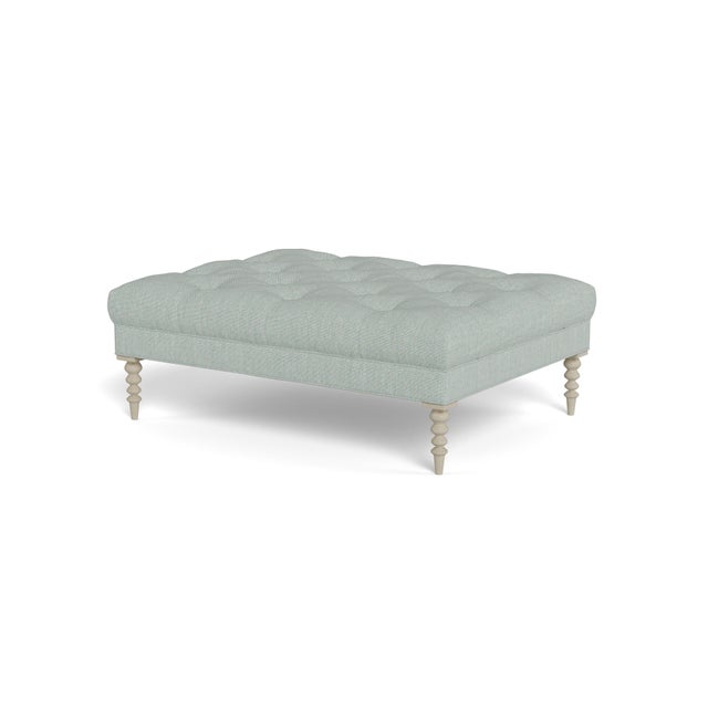 A large cocktail ottoman, with beautiful tufting set atop a trim upholstered box, with wonderfully turned legs. Legs...