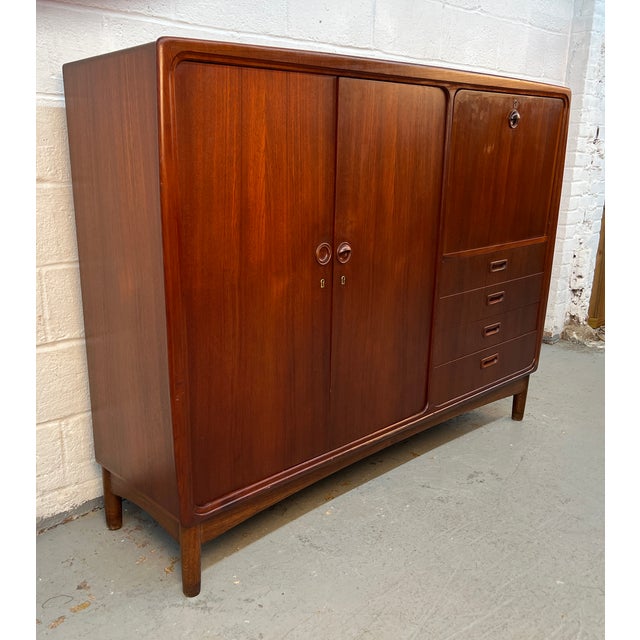 Beautiful vintage Danish Mid-Century Modern highboy gentleman’s wardrobe crafted in richly figured teak, showcasing the...