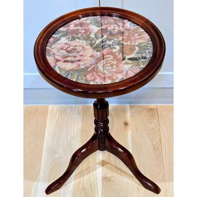 Charming Bombay Company round pedestal accent table featuring a richly stained wood frame and a glass‑topped floral...