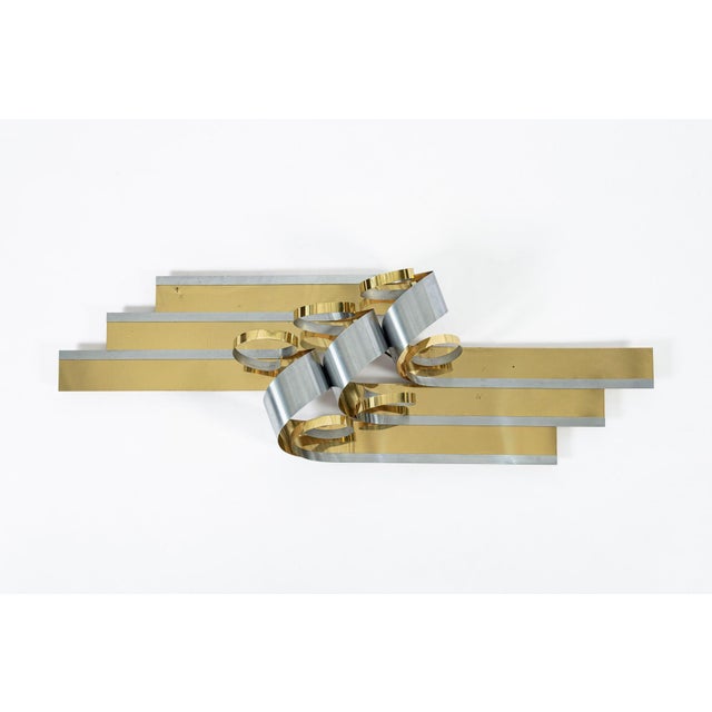This vintage mid century modern Curtis Jere metal ribbon wall art hanging sculpture features contrasting brass and silver...