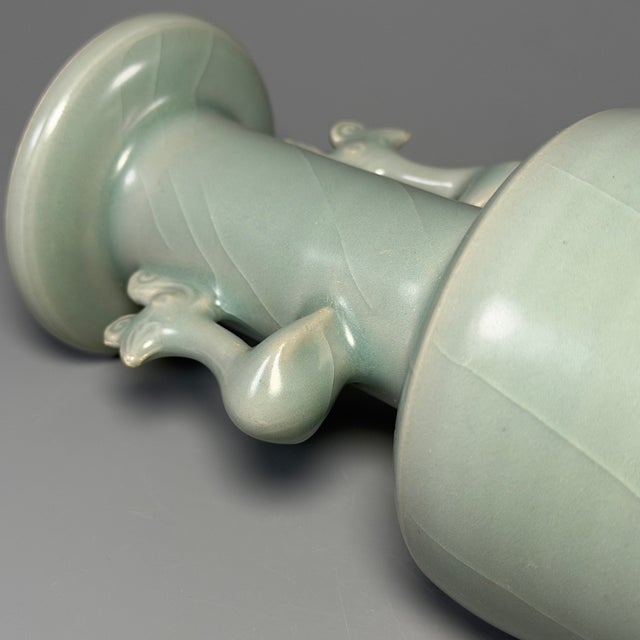 This elegant vase is crafted in classic Longquan celadon style, originating from China. It features graceful twin phoenix-...