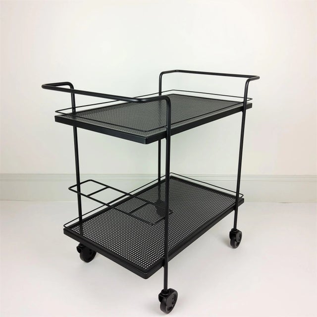 Table service Mathieu Matégot black lacquered 1950. 2 square perforated metal plates. Iron structure. Location bottles on...