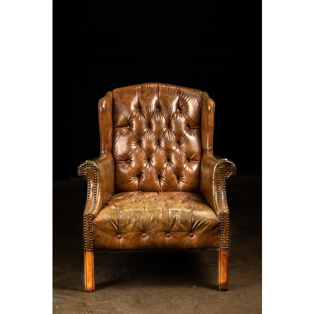 This wingback tufted chair features leather and wooden construction.
