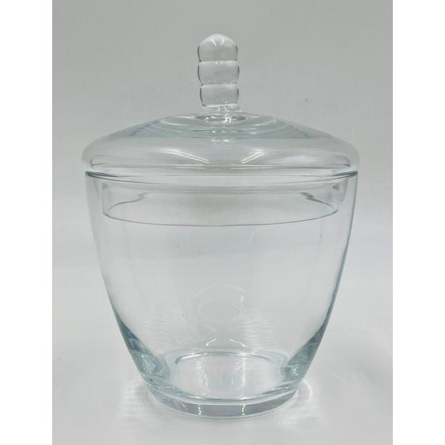 Elegant and versatile clear glass lidded vessel, designed in a timeless mid-century modern style. This sculptural candy...