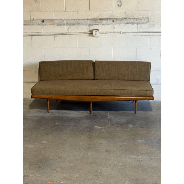 This striking armless sofa features a streamlined silhouette highlighted by an architectural exposed back support. The...