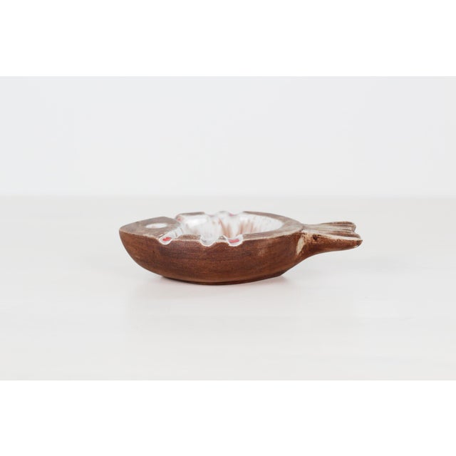 Vintage ceramic fish ashtray featuring a matte speckled brown body with a bold interior glaze — red and black drips...