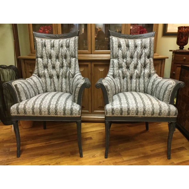 A pair of antique 1920s French style chairs painted black and distressed. Upholstered with a unique black and white faux...