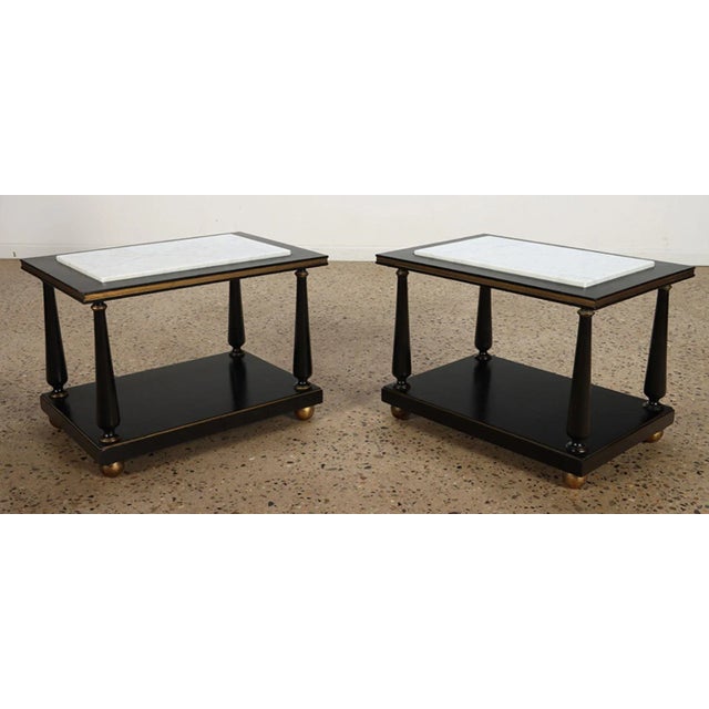A pair of ebonized and gilt marble top end tables on ball feet circa 1950.