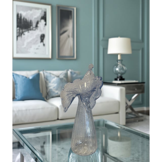 This fluted art glass vase stands 21 inches tall and 10 inches wide, rising in a long, ribbed column that opens into a...
