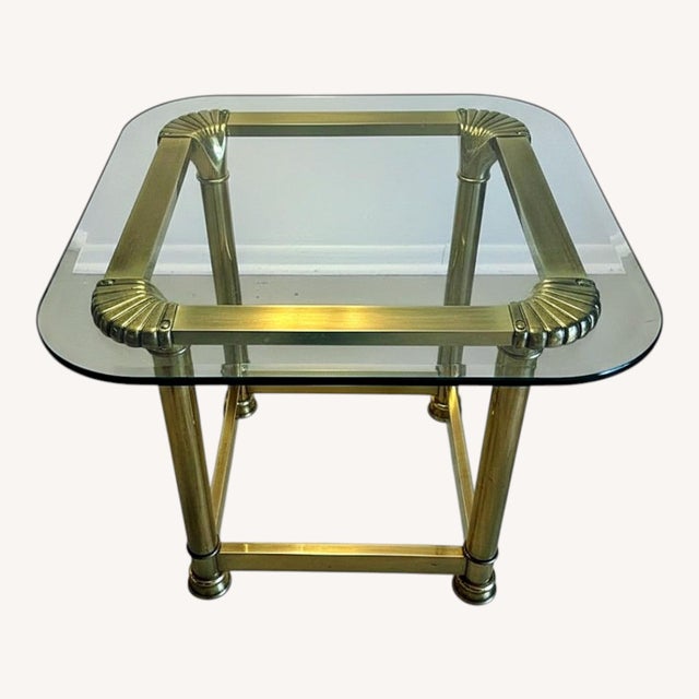 Elegant vintage 1970s Hollywood Regency brass and glass end table. This sophisticated piece features a heavy, solid brass...