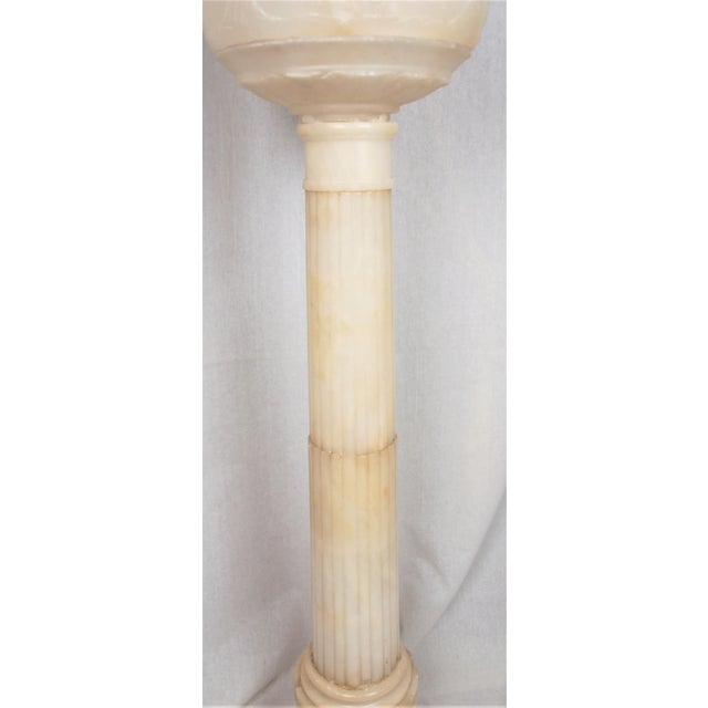 An antique large alabaster lamp with globe shade. Column is a classic ribbed style with a church key bottom outline. A...