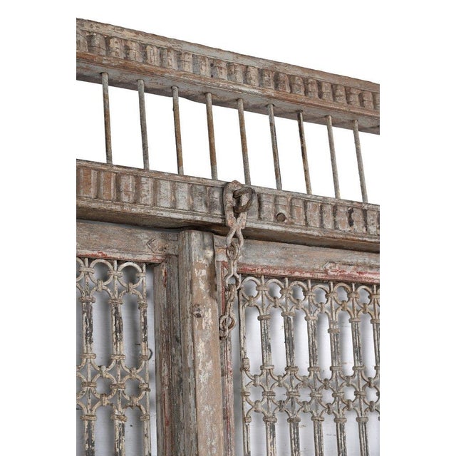 This Antique Indian Carved Teakwood and Iron Jali Door features intricate iron lattice panels, lower panels adorned with...