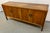 This vintage mid-century modern credenza by Henredon Furniture features a warm walnut finish and distinctive brass...