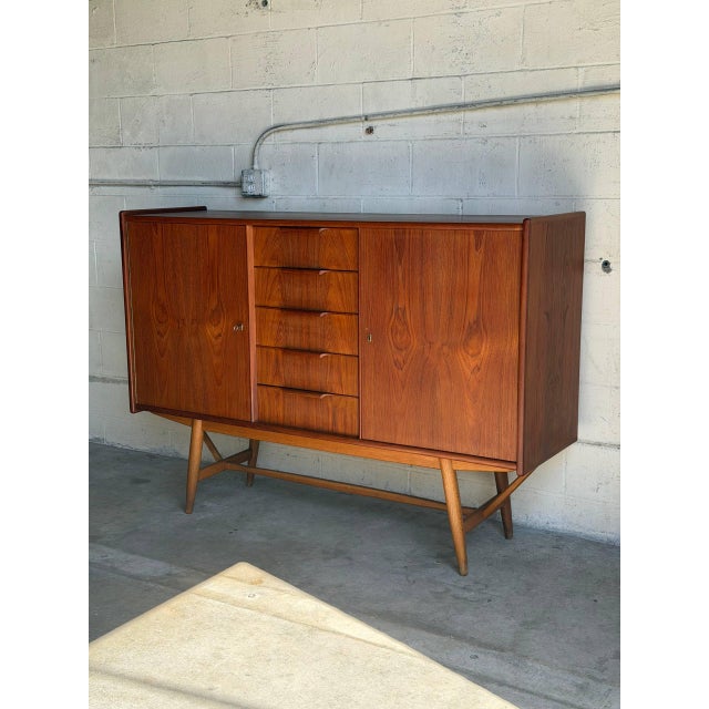 This expansive credenza features twin cabinet doors flanking five center drawers with integrated carved pulls. Raised on a...