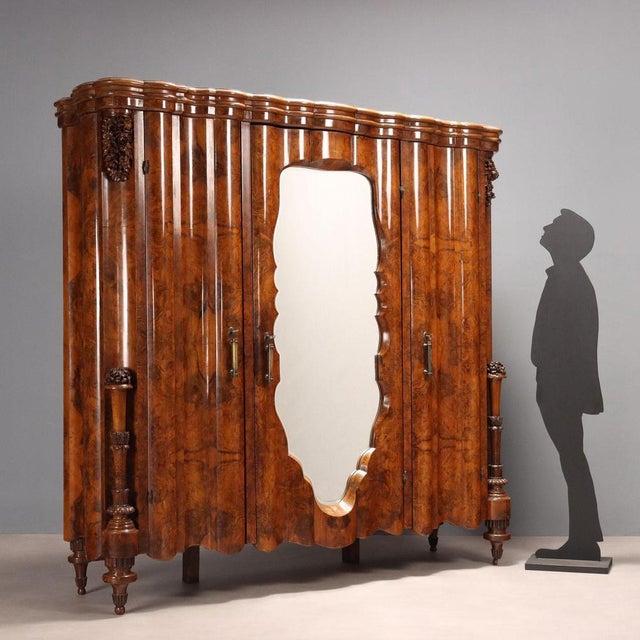 Art Deco wardrobe in walnut and walnut burl, split front with three doors, the central one featuring a beveled mirror. The...