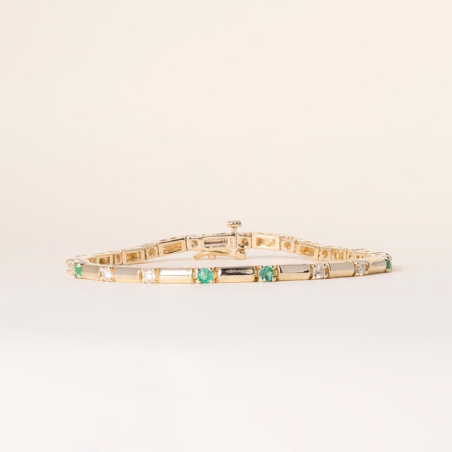 A lovely vintage line bracelet dating to the 1990s, featuring a vibrant interplay of vivid green emeralds and white...