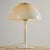 A metal table lamp with rounded shapes from the 1970s. Thanks to its lampshade, it gives off a cosy glow, making it a...