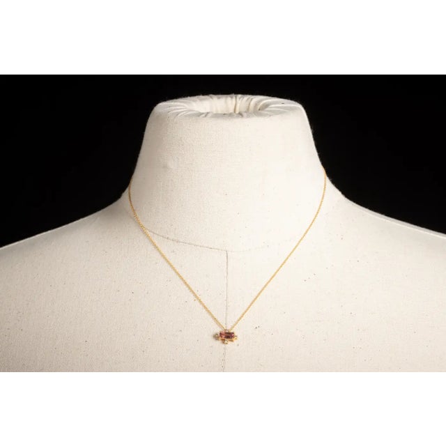 A lovely and delicate 14K gold chain necklace featuring a gold bar at the middle adorned with three heart-shaped, faceted...