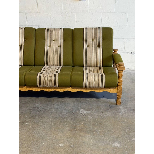 Danish three-seat sofa in style of Henning Kjærnulf, featuring solid oak construction with sculptural carved details and...