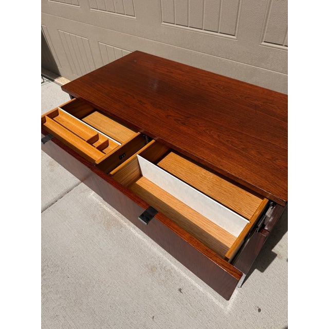 Florence Knoll-designed rosewood credenza with chrome legs and adjustable feet. This piece features a fully finished back...
