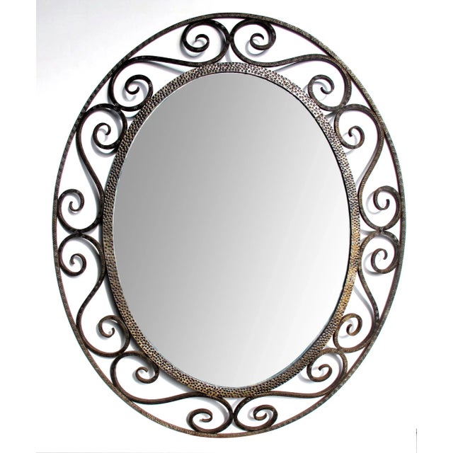 A hand-crafted French art deco openwork iron oval mirror in the style of Edgar Brandt; the oval plate within a punched...