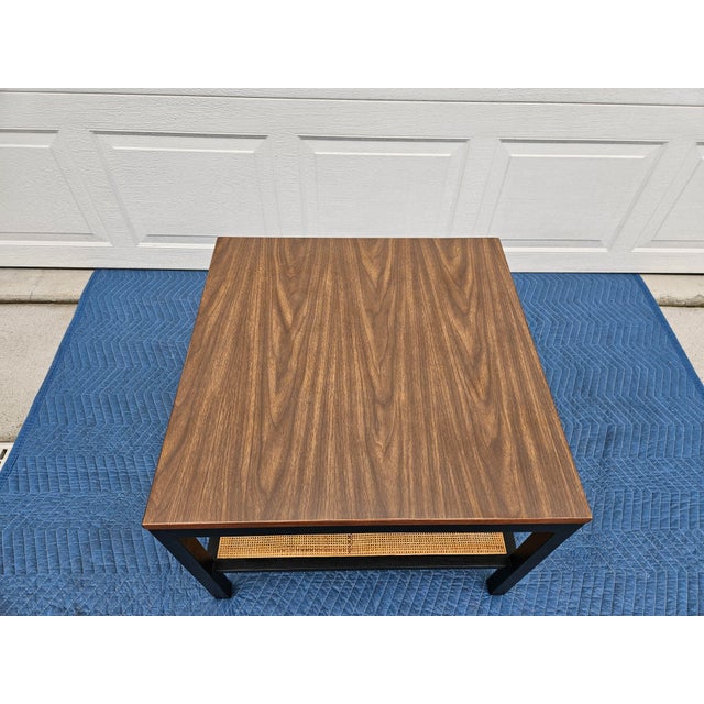 This square side table has a faux walnut laminate top, rattan lower shelf and black lacquered frame. It appears to be made...