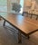 Arhaus Nika dining table. Solid wood top with a dark finish and natural wood grain details. Metal A-frame style base, dark...