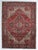 Vintage hand-knotted Persian Heriz wool rug with a red field centered by a geometric medallion in navy, ivory, and brown...