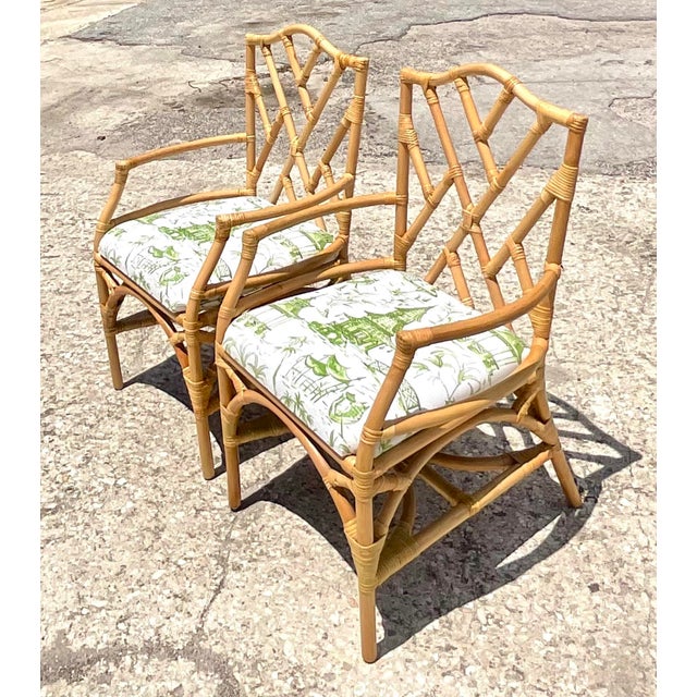 An exceptional pair of vintage Coastal rattan Chinese Chippendale armchairs, masterfully handcrafted with the timeless...