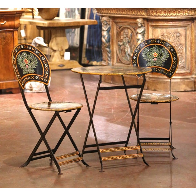 Charming and colorful, this antique French bistro set comprises a round folding table and two coordinating folding chairs....