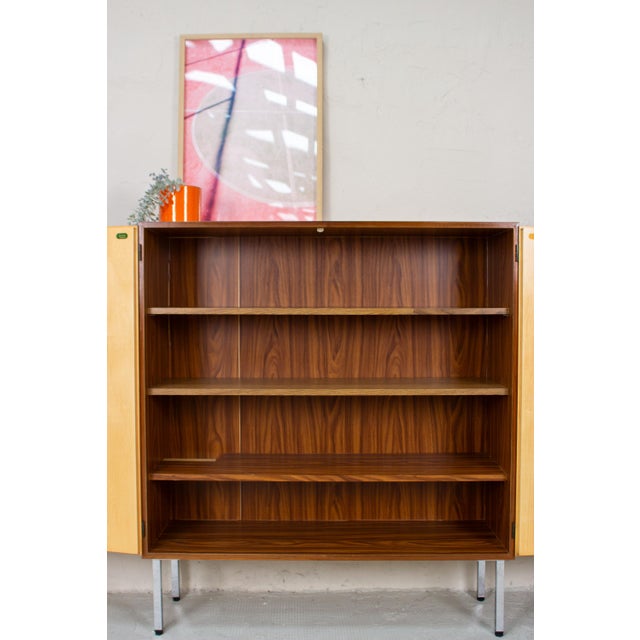 A beautiful walnut cabinet with clean lines and a warm, finely grained surface. The vertical grain extends across the two...