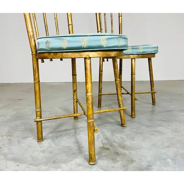 An elegant pair of Hollywood Regency gold gilt metal faux bamboo high-back accent chairs having silk bumblebee seat...