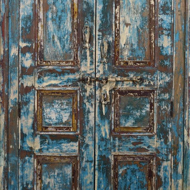 Armoire constructed from antique Indian teakwood doors and architectural elements, showcasing several worn layers of paint...