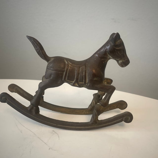 This vintage brass rocking horse features a detailed design with a dynamic pose and engraved saddle details. Its aged...