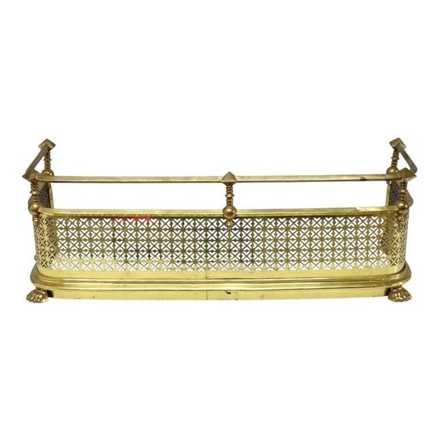 This antique brass fireplace fender, dating to approximately 1920, features a rectangular form with an intricately...