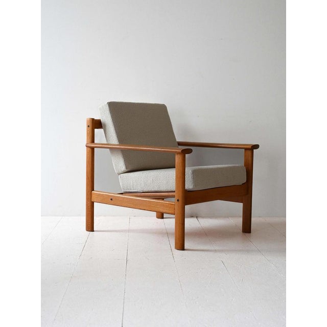 Original vintage armchair with oak structure and cushions lined with light bouclé fabric. It stands out for its typical...