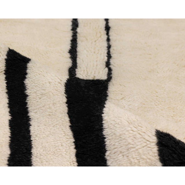 Sophisticated hand-knotted wool rug in Ivory, accented with bold geometric shapes and lines in Taupe and Midnight Black,...