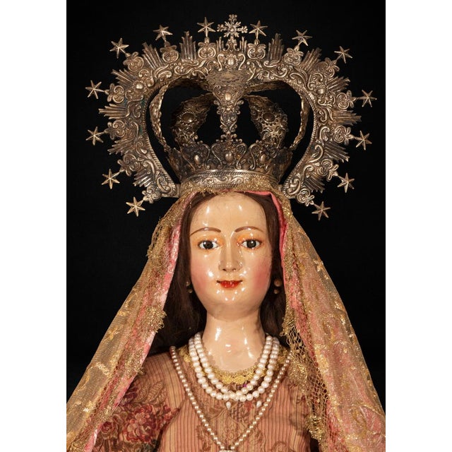 A striking Colonial Peruvian devotional sculpture depicting the Virgin of the Rosary, carved in maguey wood and presented...
