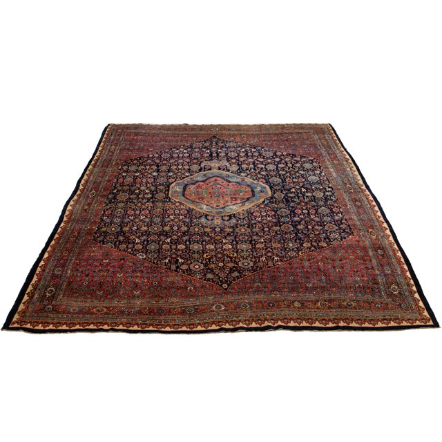 This Antique Bidjar hand-knotted wool rug has a navy blue field. It features a red frame and an all-over motif with...