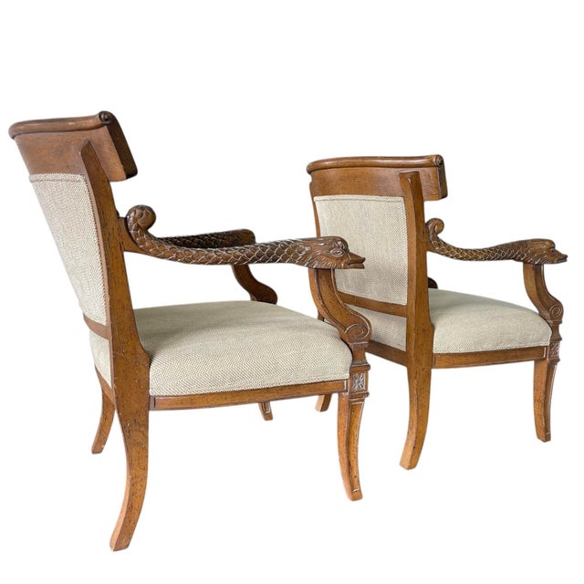 These are a pair of carved wooden armchairs in a Regency / Empire Revival style, distinguished by their bold sculptural...