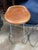 Set of four McGuire swivel counter stools featuring saddle-brown leather seats atop polished stainless steel frames. The...