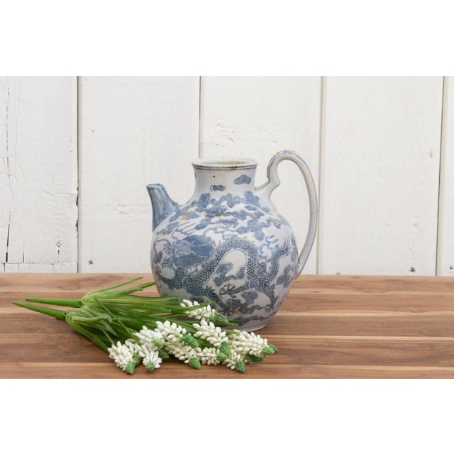 A gorgeous blue and white glazed antique wine jug. This Chinese porcelain jar has an oversized handle with a short spout....