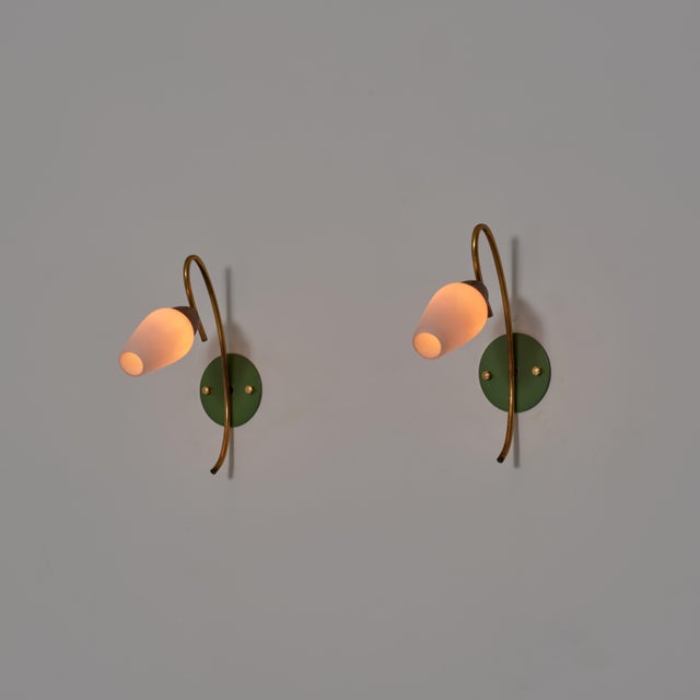 Elegant pair of italian wall sconces from the 1950s, defined by a refined and fluid composition combining brass, green...