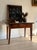 A French farmhouse table with a single drawer and original pull, tapered square legs, and a warm walnut-brown top showing...
