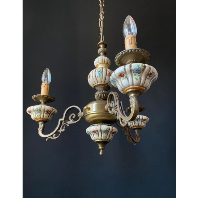 The chandelier is made of brass and bronze. It is adorned with beautiful ceramic elements featuring floral motifs. Decal...