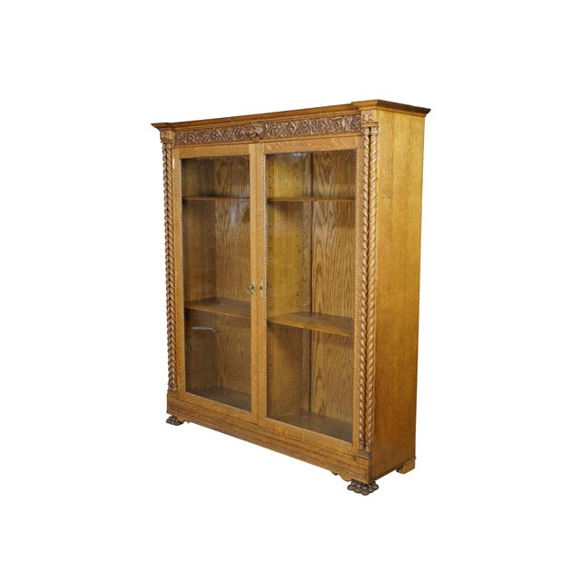This antique American Renaissance Revival bookcase or display cabinet is expertly crafted from solid oak, highlighting...