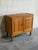 Two paneled cabinet doors open to reveal an interior storage shelf above turned legs. Brass fluted knobs add subtle detail...