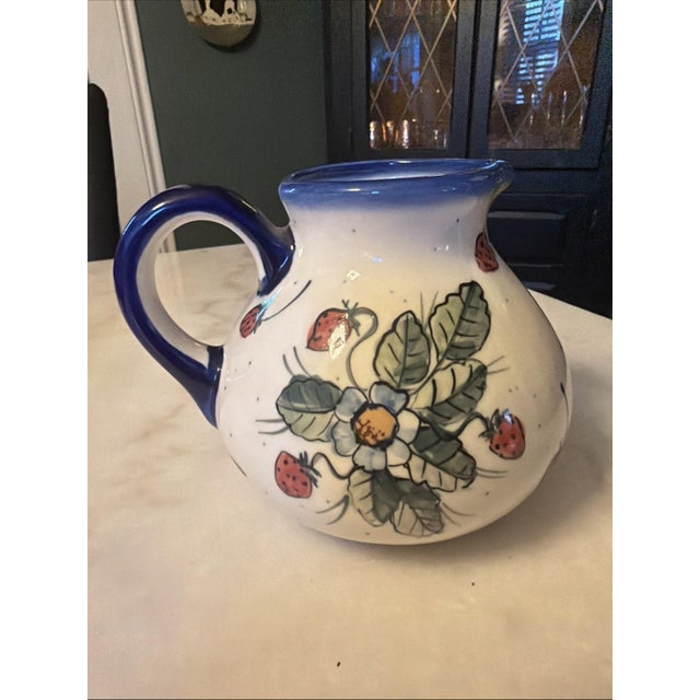 The W.R. Ceramika Unikat "Strawberries and Blossoms" Polish Pottery Pitcher is a beautifully hand-painted ceramic pitcher...